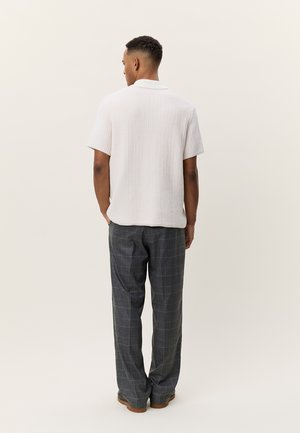 Λευκό πουκάμισο με κοντό μανίκι και υφή υφάσματος, σετ με γκρι καρό παντελόνι και καφέ παπούτσια. Φαίνεται από πίσω.