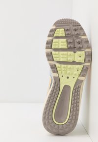Suola di scarpa sportiva con una superficie grigia texturizzata, dettagli verde lime e un battistrada multidirezionale per la trazione.