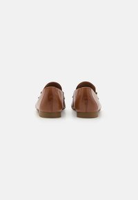 Bruine leren loafers met een ronde achterkant, platte zool en subtiele stikdetails op de bovenkant. Gladde textuur met minimale hardwareaccenten.