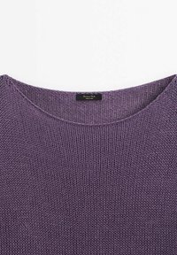 Haut à manches longues en tricot de couleur lavande douce, doté d'un col rond, d'une texture à maille lâche et d'une étiquette indiquant qu'il a été fabriqué en Chine.