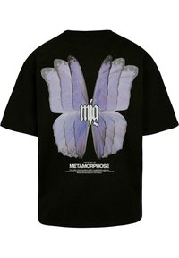 Čierne oversized tričko s veľkým, detailným grafickým dizajnom motýlích krídel v odtieňoch fialovej, s bielym textom nižšie čítajúcim "PRÍBEH METAMORFÓZY."
