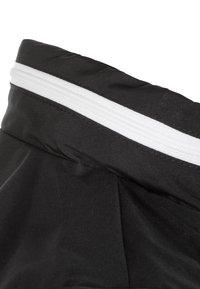 Czarny materiał z białym poziomym zamkiem błyskawicznym blisko górnej krawędzi, z widocznym szwem i szwami.