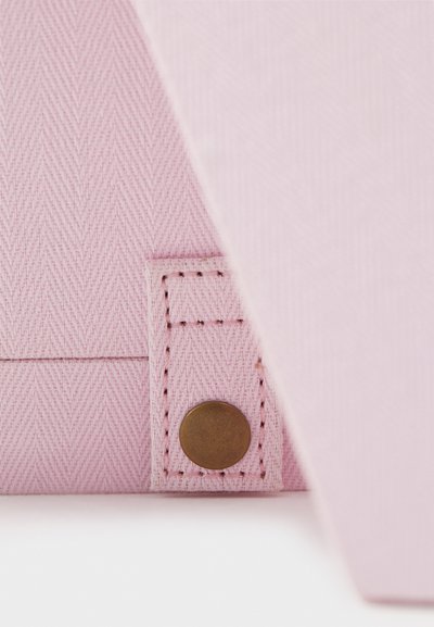 Ανοιχτό ροζ υφαντό ύφασμα με σχέδιο ψαροκόκαλο, διαθέτοντας μια ορθογώνια καπάκι και ένα αξεσουάρ με χάλκινη κουμπί σε ένα ραμμένο ταμπ. 