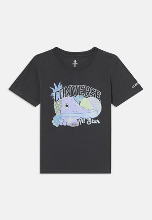 Melns kokvilnas T-krekls ar krāsainu grafiku, kurā attēlots Converse kurpes un augļi, ar "CONVERSE All Star" tekstu resnās baltās burtiem.