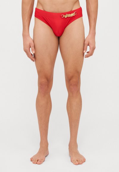 Rote Schwimmshorts aus glattem Material, mit einem goldenen "Moschino"-Logo und einem runden Hardware-Detail am Bund.