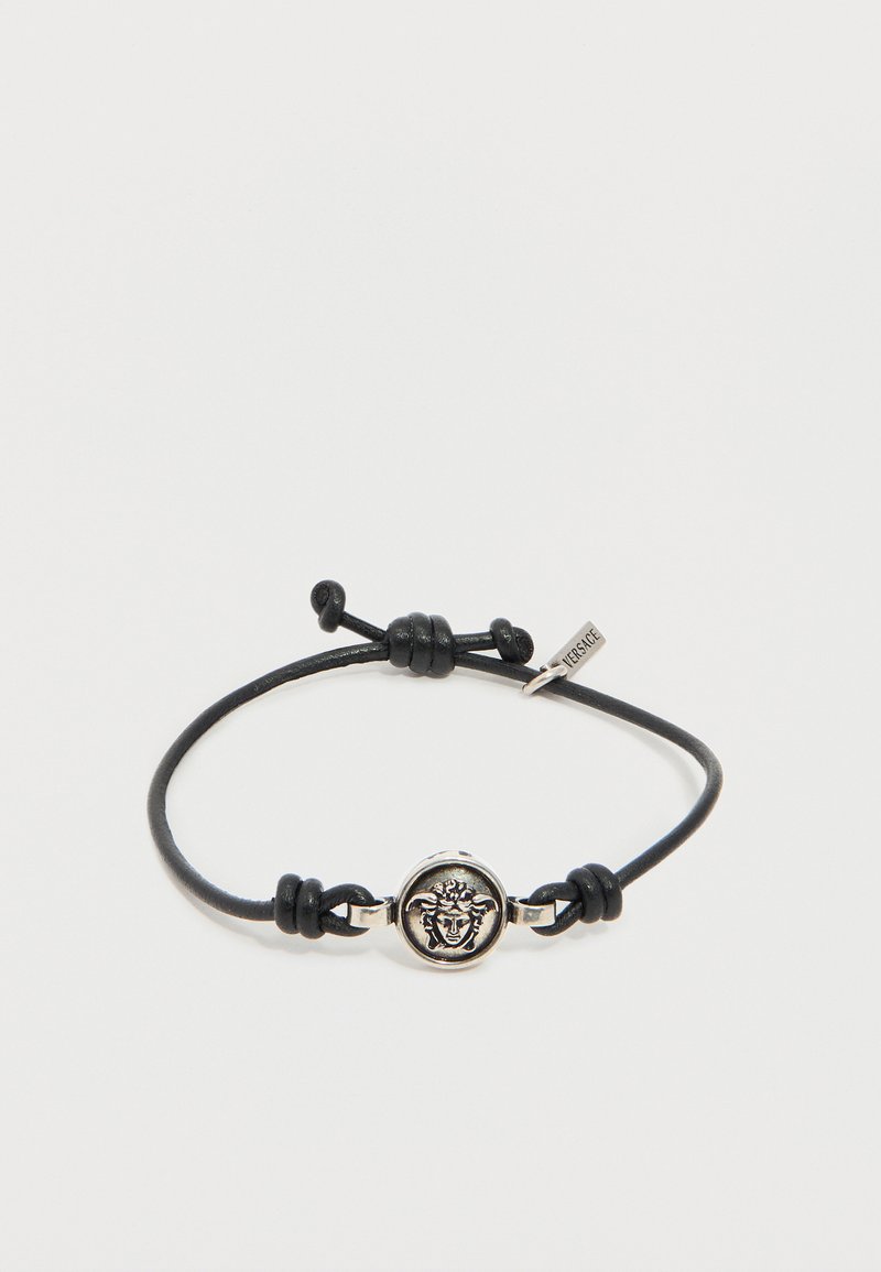 Βραχιόλι με μαύρο κορδόνι και ρυθμιζόμενους κόμπους, με ασημένιο έμβλημα κεφαλής Μέδουσας και μικρή ετικέτα Versace.