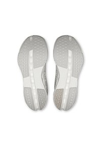 Chaussures de sport grises avec des semelles texturées présentant un motif en nid d'abeille et des accents blancs. La conception de la semelle comprend un élément de coussin d'air visible.