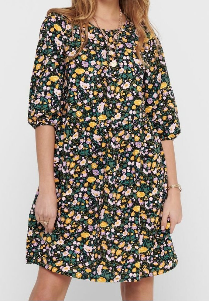 Vestido negro con estampado floral que presenta mangas cortas tipo globo, un corsé ajustado y una falda acampanada, decorado con flores amarillas, rosas y blancas sobre un fondo verde.