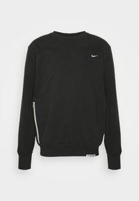 Sudadera negra de Nike hecha de tela suave, con cuello redondo, mangas largas y un detalle de cremallera lateral. Pequeño logo en el pecho.