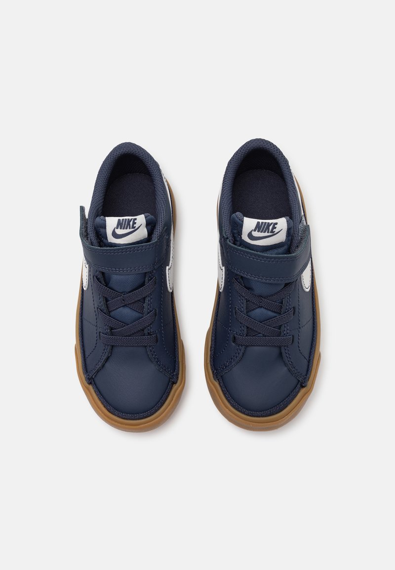 Baskets bleu marine avec une tige en cuir, des accents bleu clair et une semelle en caoutchouc marron. Elles sont dotées de lacets et d'une sangle Velcro pour un maintien sûr.