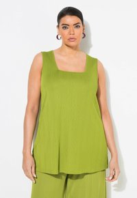 Top senza maniche di colore verde lime con scollatura quadrata. Realizzato in tessuto a coste, presenta una vestibilità ampia e rilassata che scende sotto i fianchi.