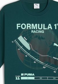 Mørkegrøn t-shirt med et Formel 1-motiv, der inkluderer en globus, racingmetrics og tekstetiketter for brems- og accelerationzoner.