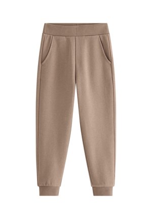 Barn iført brune joggerbukser, stribede sokker, grå og hvide sneakers, står med hænderne afslappet ned langs siderne.