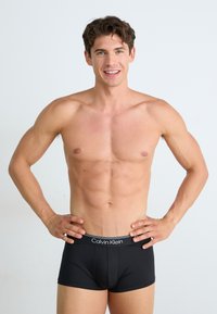 Boxer ajustados de Calvin Klein en negro con una cinturilla elástica que presenta detalles de logo. Textura suave, forma ajustada y diseño minimalista.