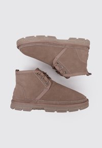 Braune Wildleder-Stiefeletten mit hohem Design, runder Spitze, zwei Ösen und einer strukturierten Gummisohle.