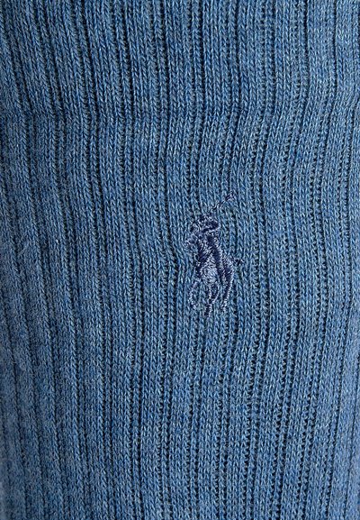 Zils ribbed adīts audums, kurā ir neliels izšūts logotips tumšākā zilā krāsā. Auduma faktūra ir mīksta, ar vertikālām svītrām visā tā virsmā.