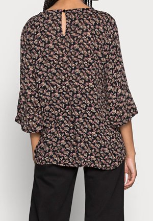 Schwarze Bluse mit floralen Mustern und Dreiviertelärmeln, die über ein Schlüssellochdetail am Ausschnitt verfügt und aus einem weichen, leichten Stoff gefertigt ist.