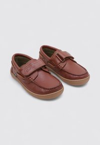 Zapatos de cuero marrón con una textura suave, que cuentan con una amplia banda de velcro y una suela de goma beige. Punta redondeada y detalles cosidos.