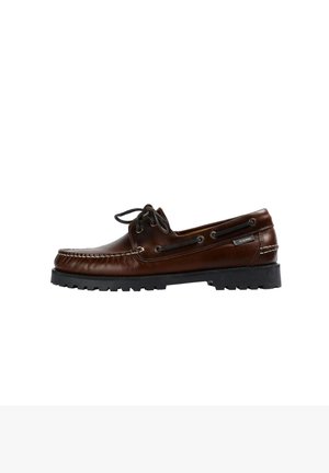 Zapato de barco de cuero marrón con punta redondeada, diseño con cordones y suela de goma texturizada. Presenta agujeros laterales y costuras decorativas.
