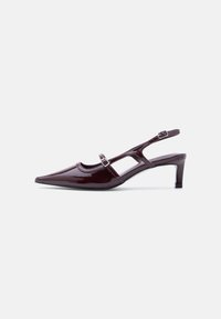 Chaussure slingback en cuir verni bordeaux avec bout pointu, talon bas et double bride à boucle réglable.