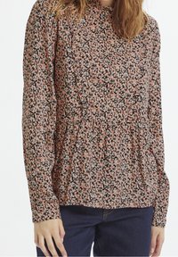 Blus med blommönster och långa ärmar, rynkad halsringning, mönster i rosa, svart och vitt, markerad midja och mjukt tyg.