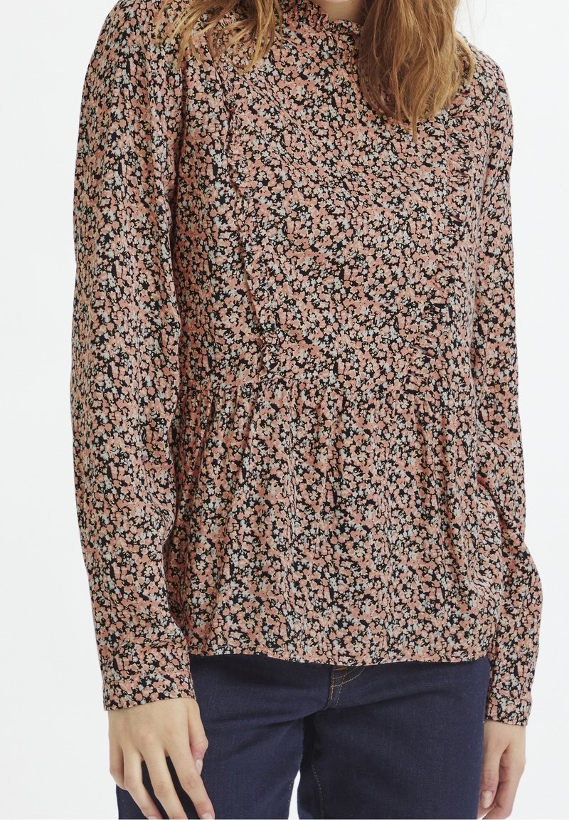 Blus med blommönster och långa ärmar, rynkad halsringning, mönster i rosa, svart och vitt, markerad midja och mjukt tyg.