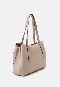 Sac fourre-tout en cuir beige avec une finition texturée, doté de deux longues anses et d'accents en métal doré. L'intérieur présente un doublure bordeaux contrastante.