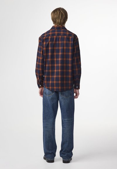 Karierte Flanellshirt in blau- und orangetönen, mit Knopfmanchetten, abgerundetem Saum und ungeformtem Design, kombiniert mit blauen Jeans.