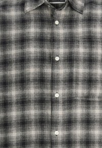 Sort-hvidternet button-up skjorte i et let materiale, med klassisk krave og fem hvide knapper ned af forsiden.