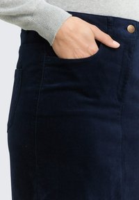 Navy Cord-Ripprock mit seitlicher Tasche, vorderem Knopfverschluss und strukturiertem Stoff. Das Design umfasst sichtbare Nähte.