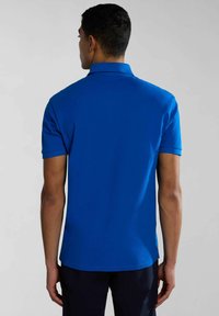 Camisa polo de manga corta en color azul, de un solo tono, con un collar clásico y un dobladillo recto. Tejido suave y ligero con un acabado pulido.