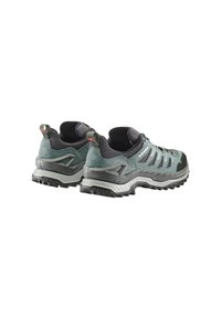 Primo piano di un paio di scarpe da trekking verdi e nere, che mette in evidenza il tessuto strutturato, le suole robuste e la struttura di supporto.
