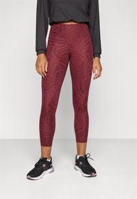 Maroon leggings with a textured animal print, high waistband, and a coordinating dark top. Paired with black athletic shoes.