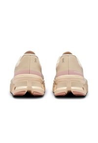 Hellrosa und beige Sport Schuhe mit einer strukturierten Oberseite, gepolstertem Fersenbereich und dickem Sohlenprofil mit pinken Akzenten. Sichtbare verstärkte Nähte.