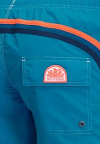 Shorts da bagno blu con una fantasia a strisce arancioni e blu navy, tasca sul retro con il logo rotondo arancione "SUNDEK" e dettagli in occhiello di metallo.