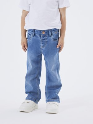 Jeans in denim azzurro chiaro con design a gamba dritta, dotati di tasche frontali e chiusura a bottone, abbinati a sneakers bianche.