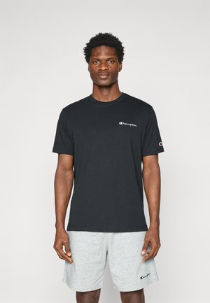 T-shirt en coton noir avec un col rond et des manches courtes, arborant un logo Champion blanc sur la poitrine et un logo gris sur la manche.