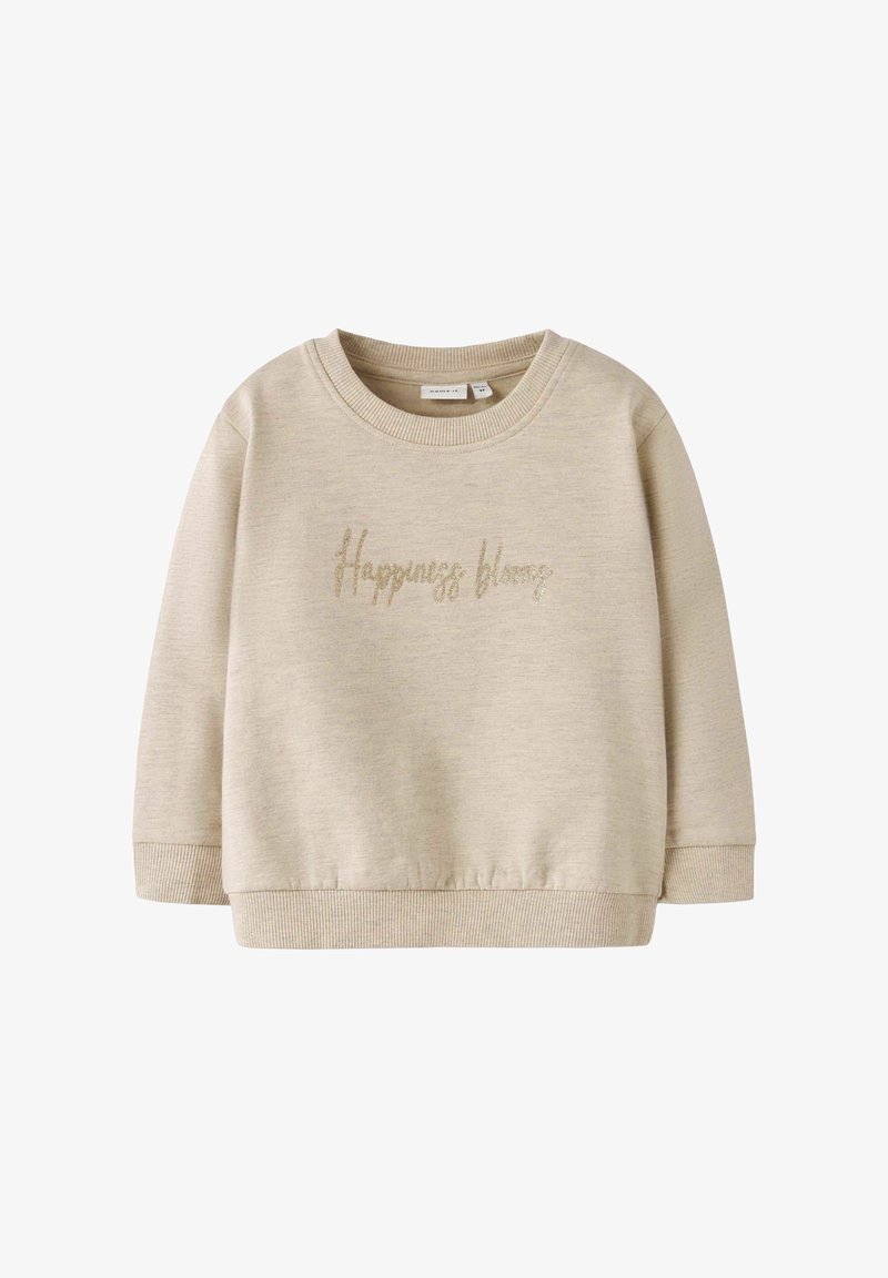 Sweatshirt beige avec un col rond et des manches longues. Il arbore l'inscription "Le bonheur fleurit" en lettres dorées scintillantes sur le devant. Texture douce.