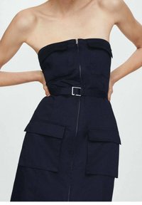 Robe sans bretelles bleu marine avec une fermeture éclair à l'avant, une ceinture à la taille et deux grandes poches plaquées. Fabriquée en tissu lisse avec une coupe structurée.