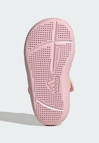 Gumová podešev v jemně růžové barvě, s texturovaným vzorem, perforacemi, drážkami pro lepší přilnavost a logem "adidas". Bez označení povrchu.