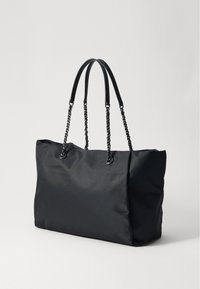 Borsa tote in nylon nero con doppi manici in pelle e dettagli in catena, caratterizzata da un corpo ampio e morbido e senza chiusure o motivi visibili.