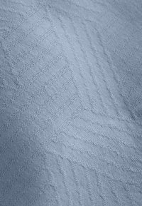 Gebreide stof in lichtblauw met een getextureerd visgraatpatroon met verhoogde steken en gladde gebieden. Zachte en rekbare textuur.