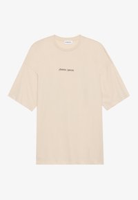 Beige katoenen t-shirt met een relaxte pasvorm, voorzien van korte mouwen en een ronde hals. "Positive Sincere" in zwart gedrukt op de voorkant.