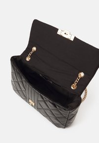 Black quilted leather handbag with a gold clasp and chain accents; interior lined with black fabric, featuring a spacious compartment.