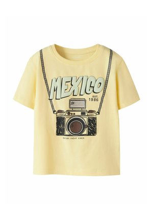 Yellow short-sleeve shirt with "MEXICO est. 1986" text and a graphic of a vintage camera with a strap and "SAFARI VACAY VIBES" below.