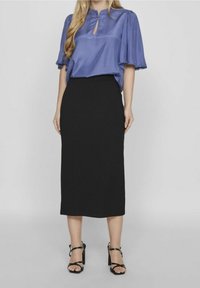 Blå satinblus med nyckelhålsutskärning och korta puffärmar, i kombination med en svart figurnära midiklänning. Svarta klacksandaler fulländar outfiten.