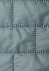 Tela acolchada de color azul claro, con una textura suave y un patrón de cuadrícula con costuras visibles. El material parece duradero y resistente al agua.