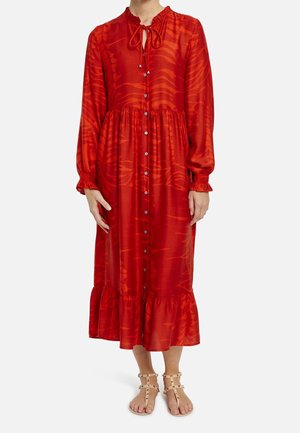 Langærmet rød midi-kjole med knapper foran, flæsekant, bindebånd i halsen, båret med beige sandaler med nitter.