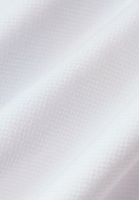 Teksturowana biała tkanina z drobnym wzorem w siatkę, prezentująca miękkie fałdy i gładką powierzchnię. Idealna do odzieży lub tapicerki.