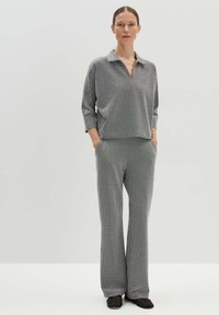 Grijs en wit gestreepte blouse met lange mouwen en kraag, gecombineerd met bijpassende wijde broek. De stof heeft een zachte textuur en een ontspannen pasvorm.